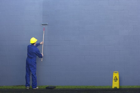 Painting a wall outside.